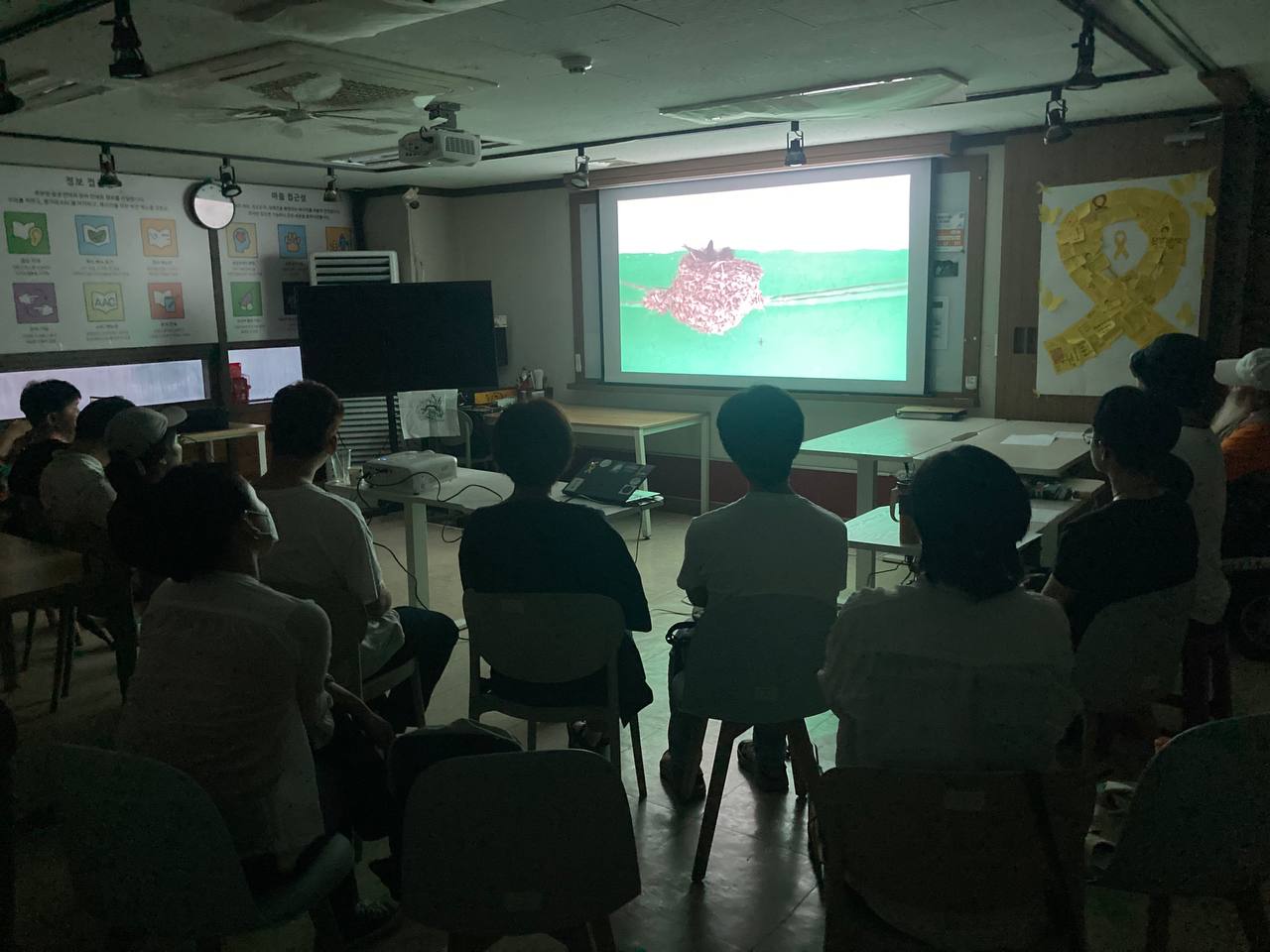 영화 공동체 상영회 상영 사진. 어두운 상영장 가운데 밝은 스크린에 제비집 클로즈업 숏이 보인다.