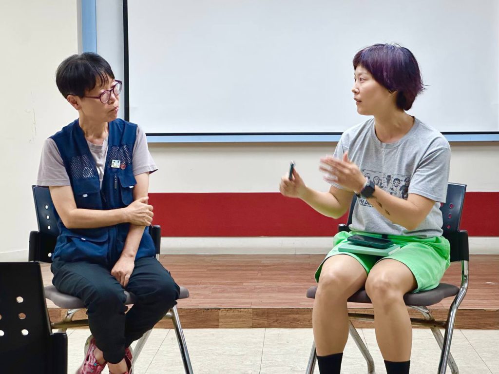 하얀 스크린 앞 의자에 각기 앉은 두 사람. 왼편의 사람은 투쟁 조끼를 입은 배태선 국장, 오른편에 앉은 사람은 편한 반팔과 반바지 차림의 들다방 예술인. 둘이 서로를 바라보며 말하고 듣는 모습