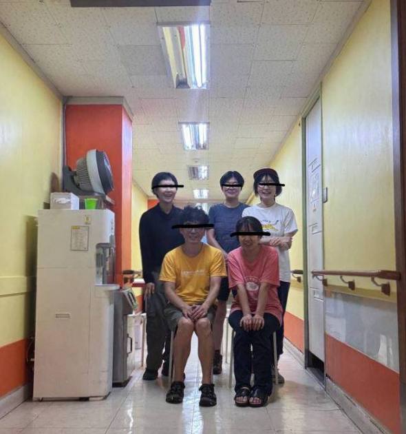 페인트칠을 마치고 함께한 분들과 찍은 기념 사진. 의자에 앉은 두 사람 뒤로 서 있는 세 사람이 피곤한 듯 활짝 웃고 있다. 양쪽 벽면이 밝은 레몬색으로 환히 빛나고 있다. 왜인지 눈에 신원을 알 수 없도록 실선이 그어져 있다. 