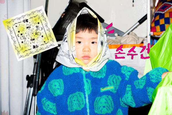 들다방 손수건을 반 접어 얼굴만 쏙 나오게 둘러 쓴 아기 상반신 클로즈업. 아기 얼굴을 가운데 두고 왼편에는 들다방 손수건 펼침면 사진이, 오른편에는 손수건이라는 글씨가 둥둥 떠 있다.