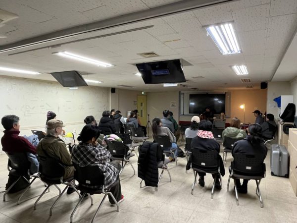 무대 앞쪽 은은한 조명이 밝혀진 가운데 동녁님이 노래하고, 그를 상영회 참가자들이 바라보는 뒷모습