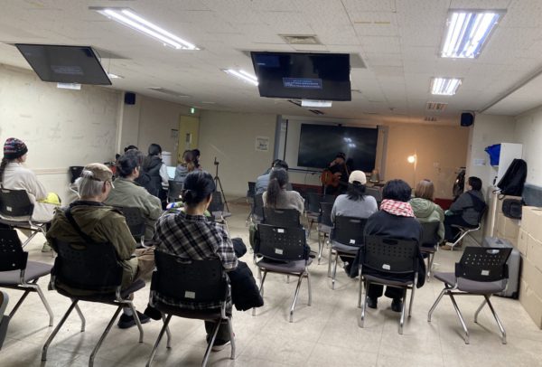 무대 앞쪽 은은한 조명이 밝혀진 가운데 동녁님이 노래하고, 그를 상영회 참가자들이 바라보는 뒷모습, 또다른 각도의 사진.