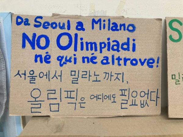 한글과 이탈리아어로 쓰인 파란 손피켓. 서울에서 밀라노까지, 올림픽은 어디에도 필요없다. Da SEOUL a Milano No Olympiadi Né qui né altrove!