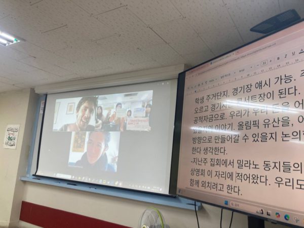 상영 후 온라인 대화 사진. 화상 대화와 문자 통역이 스크린과 액정 화면에 비춰져 있다.