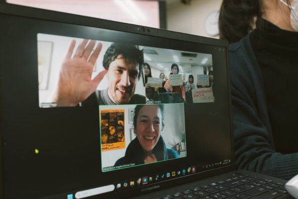 노트북 액정화면 클로즈업 사진. 줌 미팅 통한 화상 회의 중이며, 대화자는 세 명, 로렌초 마리아 그리고 한국 측 관객이 비춰지고 있다.